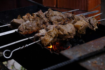 a man roasts meat on a fire. Close-up of hands and shish kebab. Cooking pork neck on the grill. Roasted carrots. Fatty food, festive food of the CIS countries. May 1, labor day. Not vegan food	