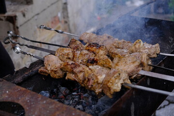 a man roasts meat on a fire. Close-up of hands and shish kebab. Cooking pork neck on the grill. Roasted carrots. Fatty food, festive food of the CIS countries. May 1, labor day. Not vegan food	