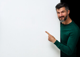 Attractive man individual indicates with index finger at white wall. Copy space. Message on the banner.