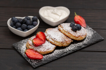 Cottage cheese cakes, sprinkled with powdered sugar and decorated with fresh berries