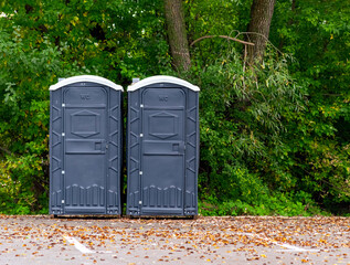 two grey public toilets in the park