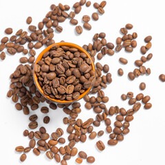 Scattered coffee beans on a white photo and a mug with coffee beans.