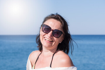 Portrait of a smiling woman in glasses at the sea. Rest, healthy lifestyle after 45 years