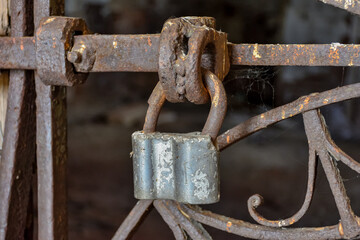 Rusty Chain Locked On Metallic Gate Against Abandoned Building