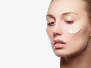 Fototapeta premium Close up beauty portrait of a laughing beautiful half naked woman applying face cream and looking away isolated over white background