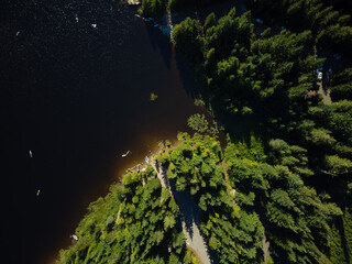 View from above. Dark water surface, high green shore, coniferous forest on the shore. Beautiful pristine nature, fresh air, ecologically clean place. Vacation, solitude.