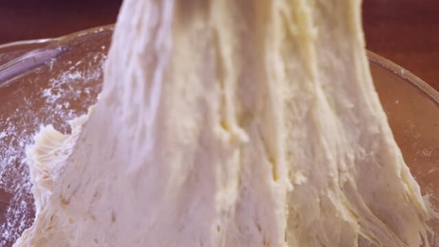 Women's hands knead the dough rolled out on the table. Medium plan