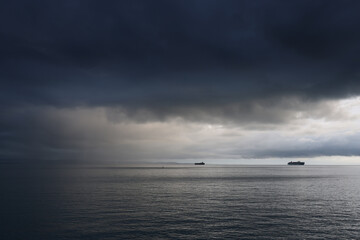 Commercial ships on the sea against the stormy sky
