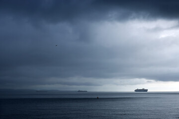 Commercial ships on the sea against the stormy sky
