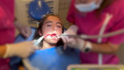 Close up of dentist hand putting elastic rubber band on patient brackets. Girl with wired metal braces on teeth receiving orthodontic treatment