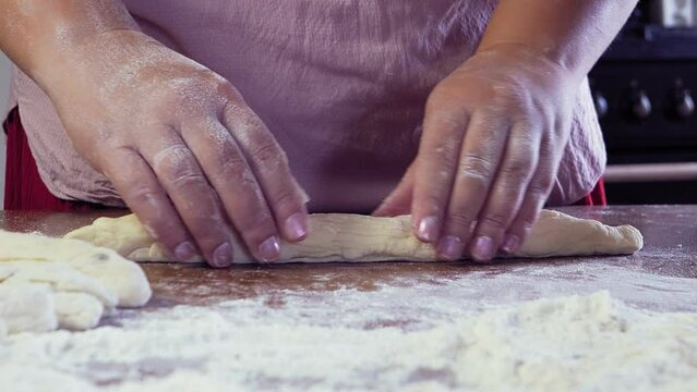 The hands of a Jewish woman form blanks of dough for the festive Challah on the table. Medium plan