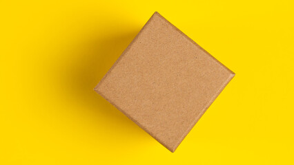 Brown craft paper or carton box with lid mock up on yellow background. Top view of blank small paper box. Brown cardboard box. Mockup photo