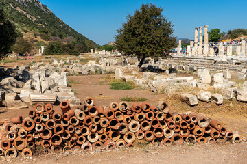 Old Roman plumbing clay pipes at Ephesus in Turkey and the ruins of the Bazilica Stoa in the...