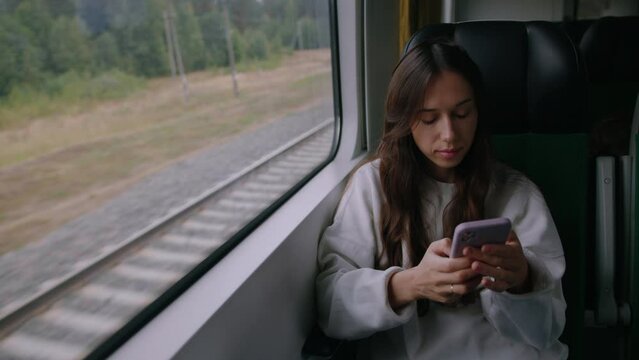 A young woman picks up the phone to text a colleague during a train ride