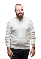 Fototapeta premium Young caucasian hipster man wearing winter sweater over isolated background winking looking at the camera with sexy expression, cheerful and happy face.