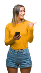 Young beautiful woman sending message using smartphone over isolated background pointing and showing with thumb up to the side with happy face smiling