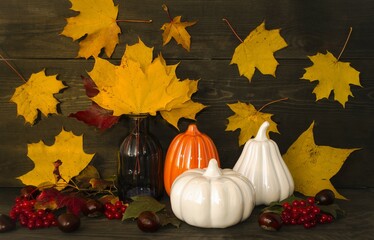 Naklejka na ściany i meble Autumn still life on a wooden background autumn leaves and berries, decorative pumpkins symbol of Halloween. The concept of decorating houses, apartments on holidays. Front view.
