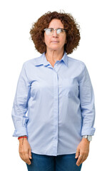 Beautiful middle ager senior businees woman wearing glasses over isolated background Relaxed with serious expression on face. Simple and natural looking at the camera.