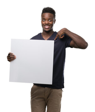 Young african american man holding a banner with surprise face pointing finger to himself