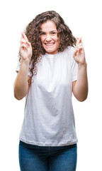 Obraz na płótnie Canvas Beautiful brunette curly hair young girl wearing casual t-shirt over isolated background smiling crossing fingers with hope and eyes closed. Luck and superstitious concept.