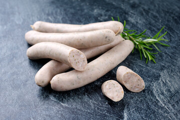 Traditional raw schweinsbratwurst offered as close-up on a grey board with text space - obrazy, fototapety, plakaty