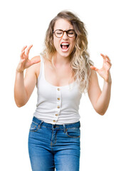 Beautiful young blonde woman wearing glasses over isolated background crazy and mad shouting and yelling with aggressive expression and arms raised. Frustration concept.