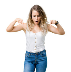 Beautiful young blonde woman over isolated background Pointing down with fingers showing advertisement, surprised face and open mouth