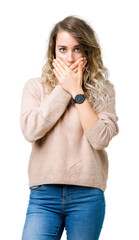 Beautiful young blonde woman wearing sweatershirt over isolated background shocked covering mouth...
