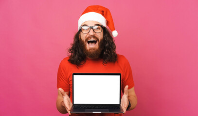 Surprised man is holding an open laptop with blank screen for Christmas offer.