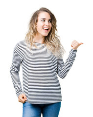 Obraz premium Beautiful young blonde woman wearing stripes sweater over isolated background smiling with happy face looking and pointing to the side with thumb up.