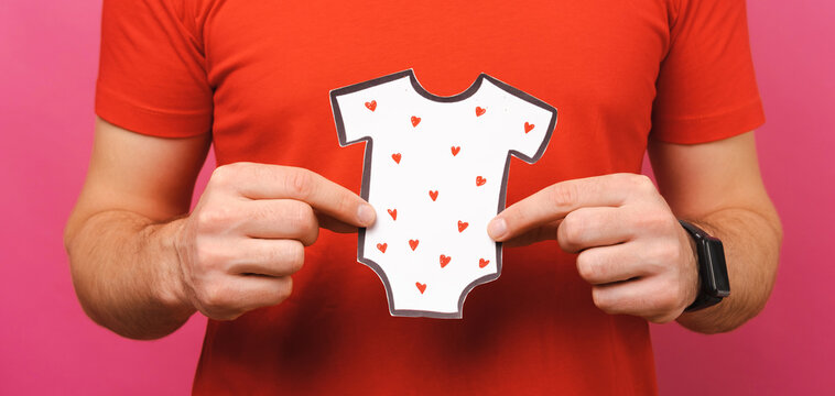 Faceless Shot Of A Male Father Holding Paper Onesie With Little Hearts.