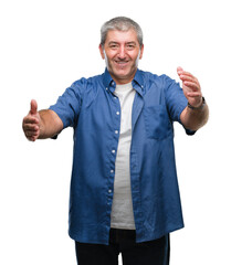 Handsome senior man over isolated background looking at the camera smiling with open arms for hug. Cheerful expression embracing happiness.