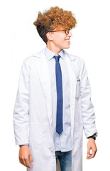 Young handsome scientist man wearing glasses looking away to side with smile on face, natural expression. Laughing confident.