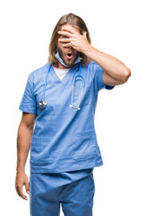 Young handsome doctor man with long hair over isolated background peeking in shock covering face and eyes with hand, looking through fingers with embarrassed expression.