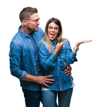 Young couple in love wearing glasses over isolated background amazed and smiling to the camera while presenting with hand and pointing with finger.