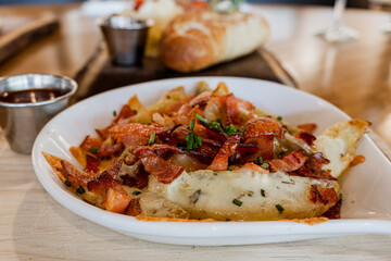 Delicious potatoes au gratin with gouda cheese and bacon strips, accompanied by chipotle jam