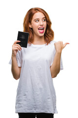 Fototapeta premium Young beautiful woman holding passport of australia over isolated background pointing and showing with thumb up to the side with happy face smiling