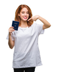 Fototapeta premium Young beautiful woman holding passport of germany over isolated background very happy pointing with hand and finger