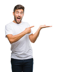 Young handsome man over isolated background amazed and smiling to the camera while presenting with hand and pointing with finger.