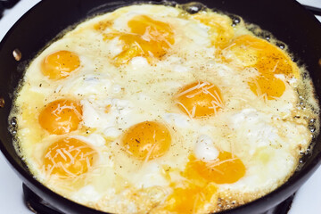 half a dozen eggs and cheese frying in a skillet