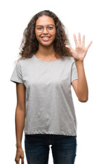Beautiful young hispanic woman wearing glasses showing and pointing up with fingers number five while smiling confident and happy.