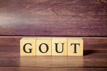 Wooden block form the word Gout with stethoscope on the doctor's desktop