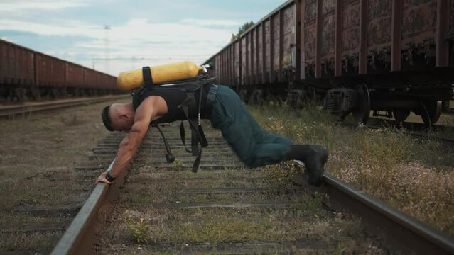 Young muscular man with balloon drager on the back doing exercise plank on rails and pulling his knees to his chest