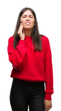Young beautiful hispanic wearing red sweater touching mouth with hand with painful expression because of toothache or dental illness on teeth. Dentist concept.
