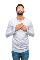 Adult hispanic man over isolated background smiling with hands on chest with closed eyes and...