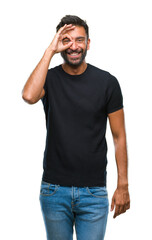 Fototapeta premium Adult hispanic man over isolated background doing ok gesture with hand smiling, eye looking through fingers with happy face.