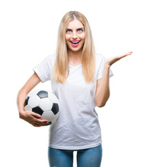 Young beautiful blonde woman holding soccer ball over isolated background very happy and excited, winner expression celebrating victory screaming with big smile and raised hands