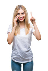 Obraz na płótnie Canvas Young beautiful blonde woman talking using smartphone over isolated background surprised with an idea or question pointing finger with happy face, number one