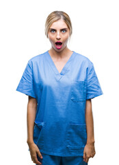 Young beautiful blonde doctor surgeon nurse woman over isolated background afraid and shocked with surprise expression, fear and excited face.