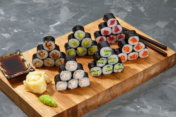 Assortment of different kinds of sushi rolls placed on black stone board. Sushi set with salmon, cucumbers, cream cheese, avocado and sesame seeds. Sushi image for menu
